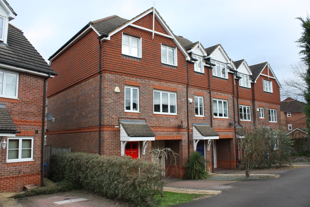 Brick and tile-clad homes with pitched roofs and landscaped front gardens
